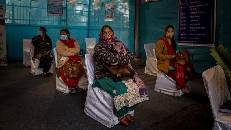 People walk past a poster placed outside a Government Hospital during a COVID-19 vaccine delivery system trial in Hyderabad, India, Saturday, Jan. 2, 2021. India tested its COVID-19 vaccine delivery system with a nationwide trial on Saturday as it prepares to roll-out an inoculation program to stem the coronavirus pandemic. Saturday's exercise included necessary data entry into an online platform for monitoring vaccine delivery, along with testing of cold storage and transportation arrangements for the vaccine, the health ministry had said.(AP Photo/Mahesh Kumar A.)
