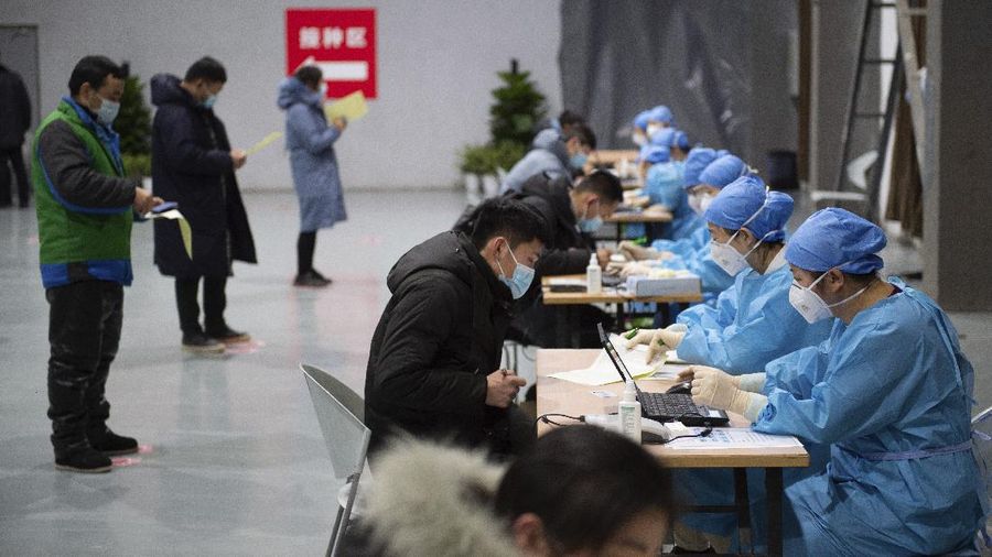 In this photo released by Xinhua News Agency, residents fill out content forms before receiving their COVID-19 vaccinations at a temporary vaccination site in Beijing, Saturday, Jan. 2, 2021. China authorized its first homegrown COVID-19 vaccine for general use on Dec. 31, 2020, adding another shot that could see wide use in poorer countries as the virus surges back around the globe. (Chen Zhonghao/Xinhua via AP)