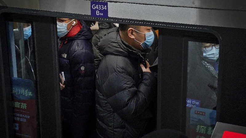 People wearing face masks to help curb the spread of the coronavirus walk on a pedestrian bridge against the Central Business District in Beijing, Tuesday, Jan. 5, 2021. Wary of another wave of infections, China is urging tens of millions of migrant workers to stay put during next month's Lunar New Year holiday, usually the world's largest annual human migration. (AP Photo/Andy Wong)