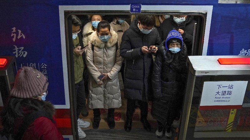 People wearing face masks to help curb the spread of the coronavirus walk on a pedestrian bridge against the Central Business District in Beijing, Tuesday, Jan. 5, 2021. Wary of another wave of infections, China is urging tens of millions of migrant workers to stay put during next month's Lunar New Year holiday, usually the world's largest annual human migration. (AP Photo/Andy Wong)
