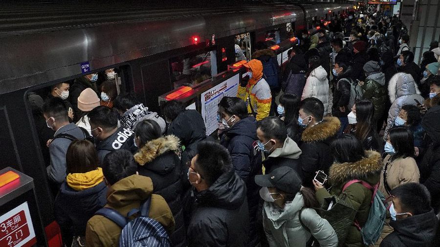 People wearing face masks to help curb the spread of the coronavirus walk on a pedestrian bridge against the Central Business District in Beijing, Tuesday, Jan. 5, 2021. Wary of another wave of infections, China is urging tens of millions of migrant workers to stay put during next month's Lunar New Year holiday, usually the world's largest annual human migration. (AP Photo/Andy Wong)