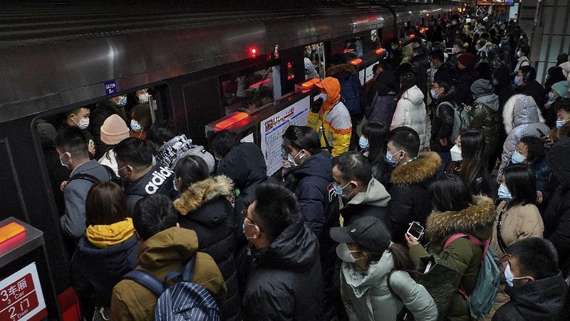 People wearing face masks to help curb the spread of the coronavirus walk on a pedestrian bridge against the Central Business District in Beijing, Tuesday, Jan. 5, 2021. Wary of another wave of infections, China is urging tens of millions of migrant workers to stay put during next month's Lunar New Year holiday, usually the world's largest annual human migration. (AP Photo/Andy Wong)