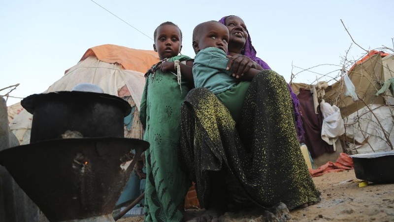 An internal displaced woman with her children cooks food near their makeshift shelter in Daynile camp in Mogadishu, Somalia on Thursday Dec. 17, 2020. As richer countries race to distribute COVID-19 vaccines, Somalia remains the rare place where much of the population hasn't taken the coronavirus seriously. Some fear that’s proven to be deadlier than anyone knows. (AP Photo/Farah Abdi Warsameh)