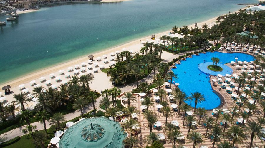 The pool and beach of the Atlantis Hotel is seen with the skyline of the Dubai Marina visible in the distance in Dubai, United Arab Emirates, Tuesday, July 14, 2020. Dubai has reopened for tourists, including at the Atlantis on Dubai's man-made Palm Jumeirah archipelago, though workers there expect a slow growth through the rest of the year amid the ongoing coronavirus pandemic. (AP Photo/Jon Gambrell)