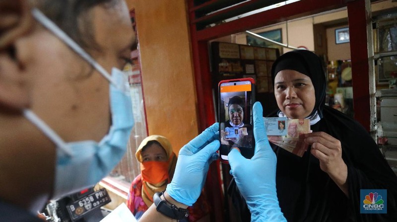 Petugas Pos Indonesia menyalurkankan bantuan sosial (bansos) ke pemukiman di wilayah Kenari, Jakarta Pusat, Rabu (6/1/2021). Pemerintah telah meresmikan penyaluran bantuan tunai se-Indonesia hari ini.  (CNBC Indonesia/Andrean Kristianto)