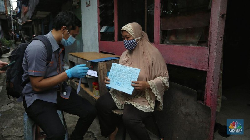 Petugas Pos Indonesia menyalurkankan bantuan sosial (bansos) ke pemukiman di wilayah Kenari, Jakarta Pusat, Rabu (6/1/2021). Pemerintah telah meresmikan penyaluran bantuan tunai se-Indonesia hari ini.  (CNBC Indonesia/Andrean Kristianto)