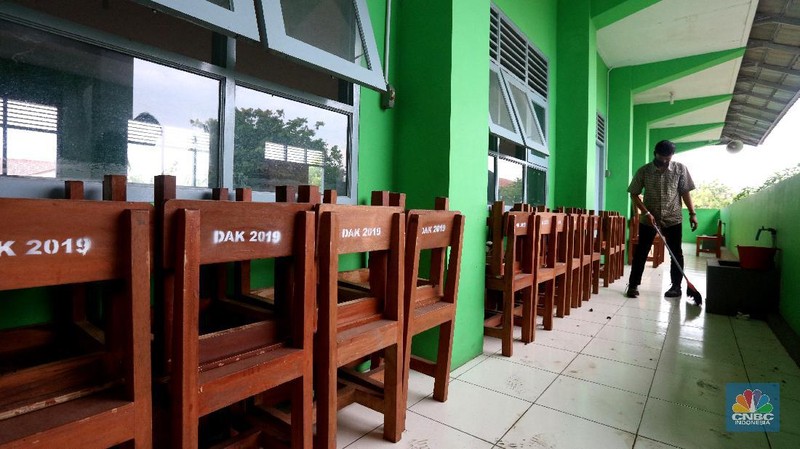 Penjaga sekolah membereskan ruang sekolah yang kosong di Depok, Jawa barat, Rabu (6/1/2021). Kegitan pembelajaran secara tatap muka di wilayah Jawa Barat yang direncanakan dimulai pada awal bulan Januari 2021 ditunda dengan batas waktu yang belum ditentukan akibat masih tingginya kasus Covid-19. (CNBC Indonesia/Tri Susilo).