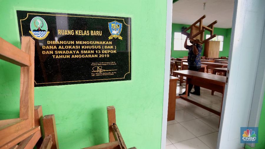 Penjaga sekolah membereskan ruang sekolah yang kosong di Depok, Jawa barat, Rabu (6/1/2021). Kegitan pembelajaran secara tatap muka di wilayah Jawa Barat yang direncanakan dimulai pada awal bulan Januari 2021 ditunda dengan batas waktu yang belum ditentukan akibat masih tingginya kasus Covid-19. (CNBC Indonesia/Tri Susilo).