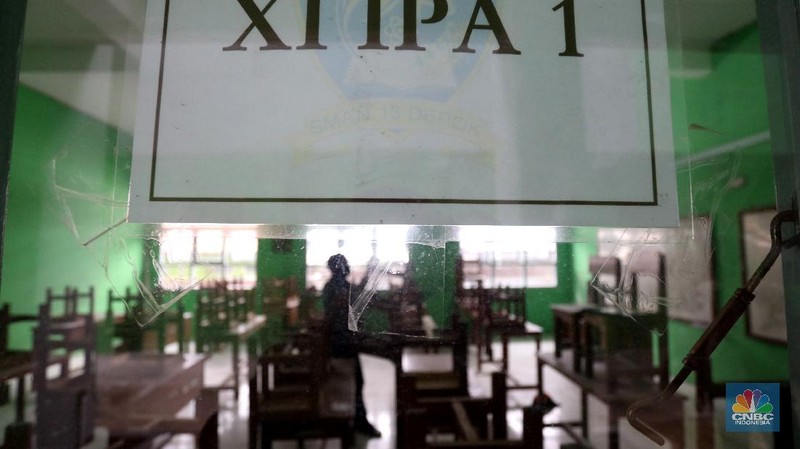 Penjaga sekolah membereskan ruang sekolah yang kosong di Depok, Jawa barat, Rabu (6/1/2021). Kegitan pembelajaran secara tatap muka di wilayah Jawa Barat yang direncanakan dimulai pada awal bulan Januari 2021 ditunda dengan batas waktu yang belum ditentukan akibat masih tingginya kasus Covid-19. (CNBC Indonesia/Tri Susilo).