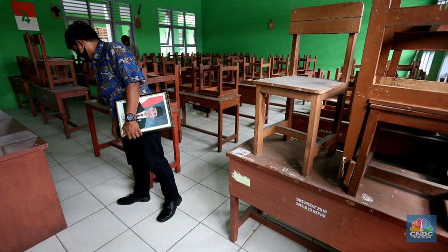 Penjaga sekolah membereskan ruang sekolah yang kosong di Depok, Jawa barat, Rabu (6/1/2021). Kegitan pembelajaran secara tatap muka di wilayah Jawa Barat yang direncanakan dimulai pada awal bulan Januari 2021 ditunda dengan batas waktu yang belum ditentukan akibat masih tingginya kasus Covid-19. (CNBC Indonesia/Tri Susilo).