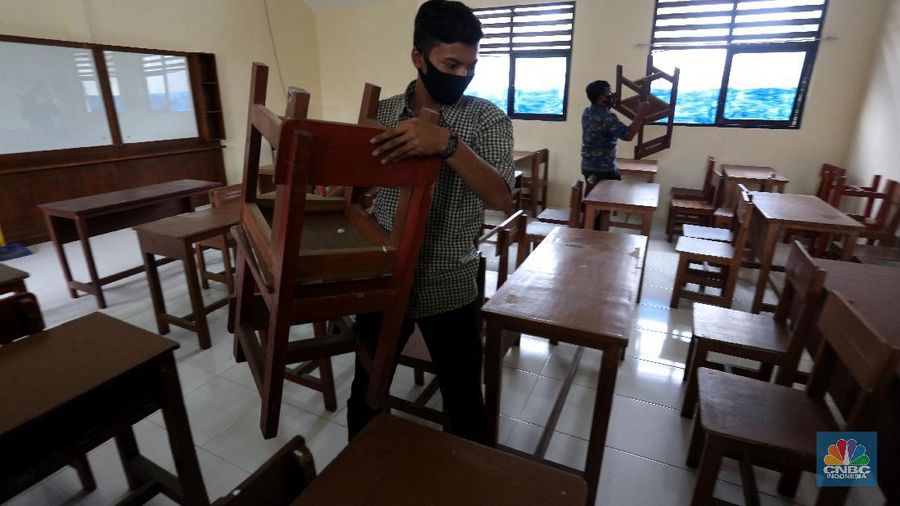 Penjaga sekolah membereskan ruang sekolah yang kosong di Depok, Jawa barat, Rabu (6/1/2021). Kegitan pembelajaran secara tatap muka di wilayah Jawa Barat yang direncanakan dimulai pada awal bulan Januari 2021 ditunda dengan batas waktu yang belum ditentukan akibat masih tingginya kasus Covid-19. (CNBC Indonesia/Tri Susilo).