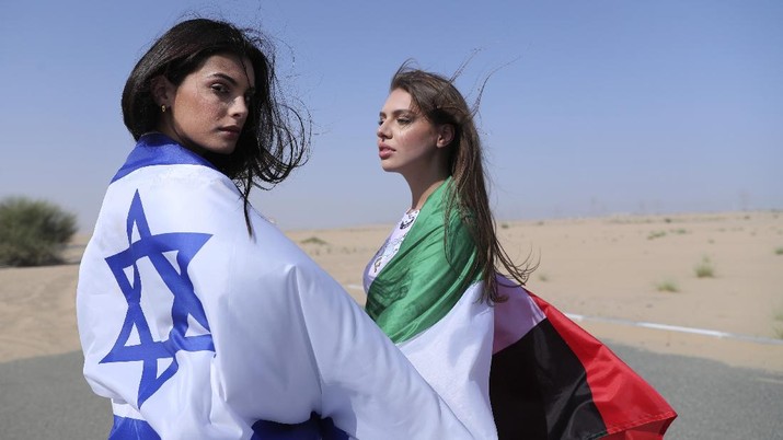 Israeli model May Tager, left, covers herself with an Israeli flag next to Anastasia Bandarenka, a Dubai-based model who covers herself in a UAE flag on the set of a photo shoot in Dubai, United Arab Emirates, Sunday, Sept. 8, 2020. (AP Photo/Kamran Jebreili)