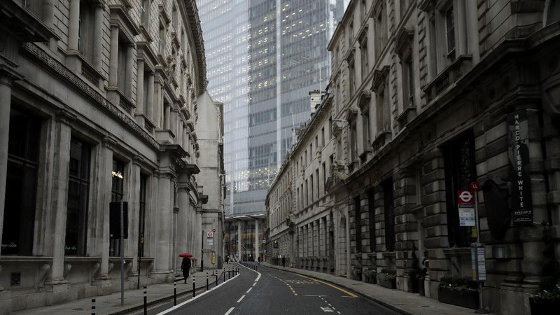 A man walks backdropped by the Bank of England in the City of London financial district in London, Jan. 5, 2021, on the first morning of England entering a third national lockdown since the coronavirus outbreak began. British Prime Minister Boris Johnson on Monday night announced a tough new stay-at-home order that will last at least six weeks, as authorities struggle to stem a surge in COVID-19 infections that threatens to overwhelm hospitals around the U.K. (AP Photo/Matt Dunham)