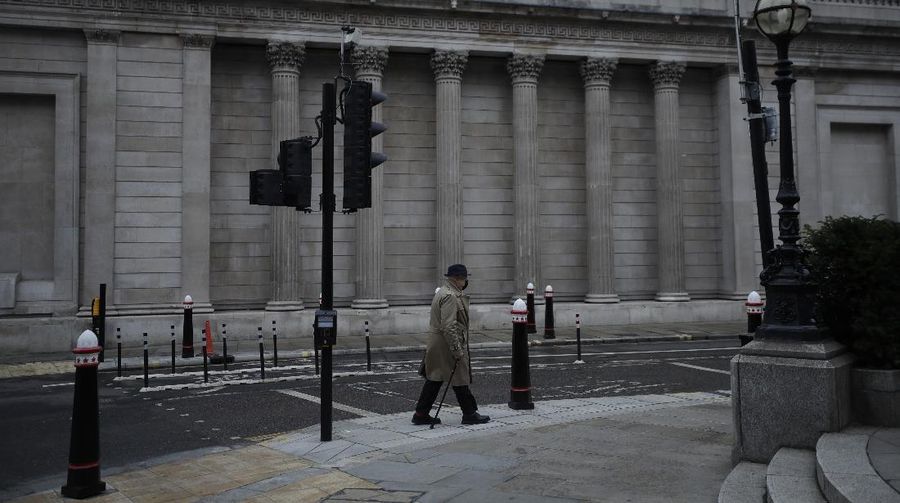 A man walks backdropped by the Bank of England in the City of London financial district in London, Jan. 5, 2021, on the first morning of England entering a third national lockdown since the coronavirus outbreak began. British Prime Minister Boris Johnson on Monday night announced a tough new stay-at-home order that will last at least six weeks, as authorities struggle to stem a surge in COVID-19 infections that threatens to overwhelm hospitals around the U.K. (AP Photo/Matt Dunham)