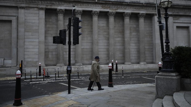 A man walks backdropped by the Bank of England in the City of London financial district in London, Jan. 5, 2021, on the first morning of England entering a third national lockdown since the coronavirus outbreak began. British Prime Minister Boris Johnson on Monday night announced a tough new stay-at-home order that will last at least six weeks, as authorities struggle to stem a surge in COVID-19 infections that threatens to overwhelm hospitals around the U.K. (AP Photo/Matt Dunham)