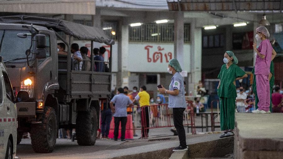 Medical workers watch as migrant workers and their families are prepared to be taken to a field hospital for COVID-19 patents in Samut Sakhon, South of Bangkok, Thailand, Monday, Jan. 4, 2021. For much of 2020, Thailand had the coronavirus under control. After a strict nationwide lockdown in April and May, the number of new local infections dropped to zero, where they remained for the next six months. However, a new outbreak discovered in mid-December threatens to put Thailand back where it was in the toughest days of early 2020. (AP Photo/Gemunu Amarasinghe)
