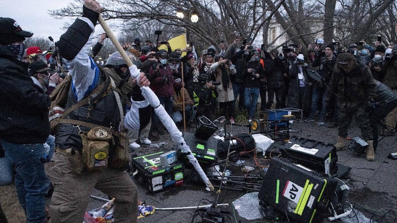Demonstrators break TV equipment outside the the U.S. Capitol on Wednesday, Jan. 6, 2021, in Washington.  (AP Photo/Jose Luis Magana)