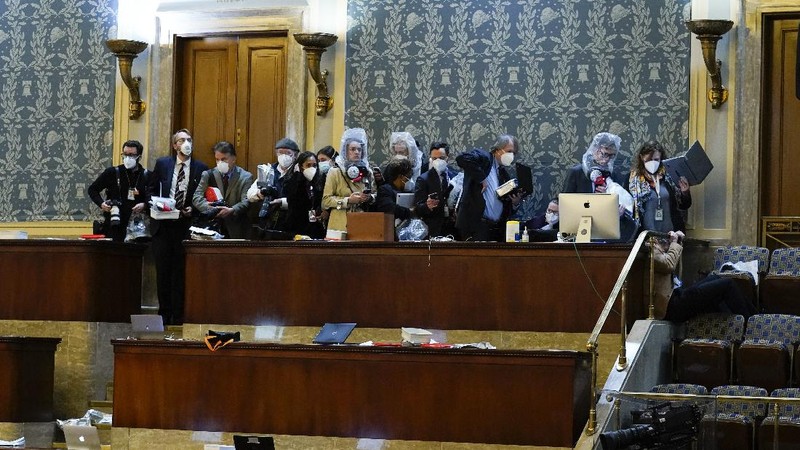 People shelter in the House gallery as protesters try to break into the House Chamber at the U.S. Capitol on Wednesday, Jan. 6, 2021, in Washington. (AP Photo/Andrew Harnik)