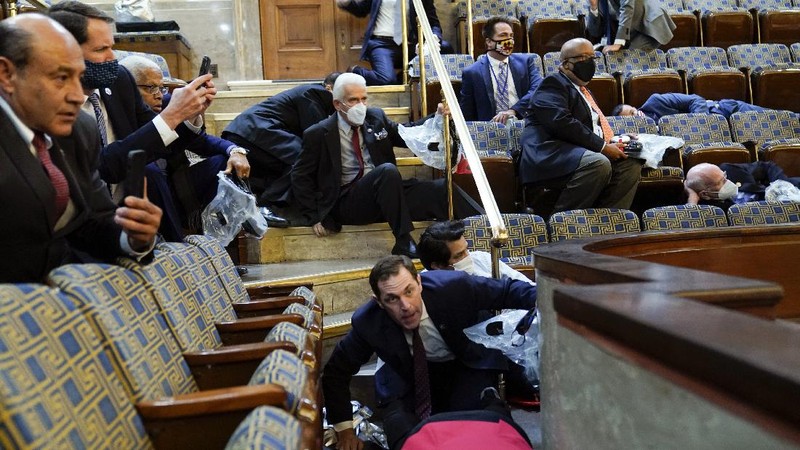 People shelter in the House gallery as protesters try to break into the House Chamber at the U.S. Capitol on Wednesday, Jan. 6, 2021, in Washington. (AP Photo/Andrew Harnik)