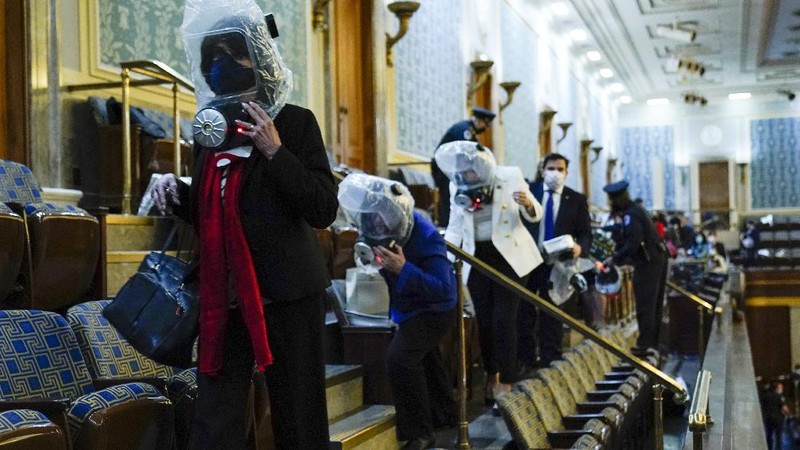 People shelter in the House gallery as protesters try to break into the House Chamber at the U.S. Capitol on Wednesday, Jan. 6, 2021, in Washington. (AP Photo/Andrew Harnik)