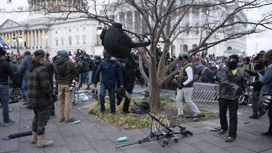 Protesters break television equipment outside the the U.S. Capitol on Wednesday, Jan. 6, 2021, in Washington. (AP Photo/Jose Luis Magana)