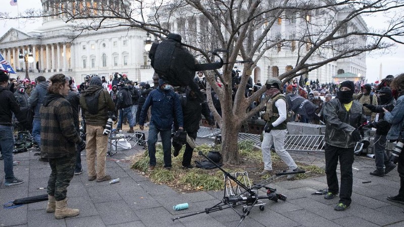 Demonstrators break TV equipment outside the the U.S. Capitol on Wednesday, Jan. 6, 2021, in Washington.  (AP Photo/Jose Luis Magana)