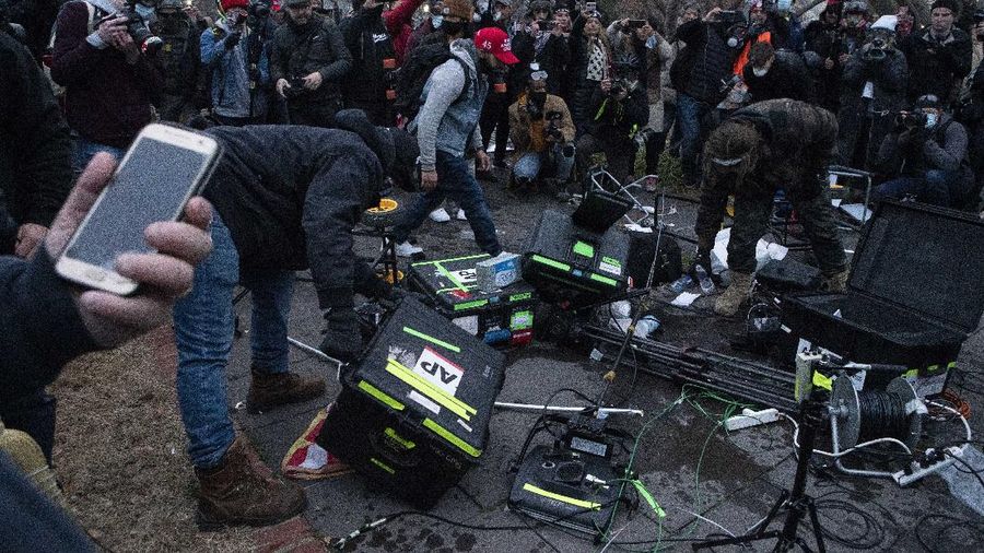Demonstrators break TV equipment outside the the U.S. Capitol on Wednesday, Jan. 6, 2021, in Washington.  (AP Photo/Jose Luis Magana)