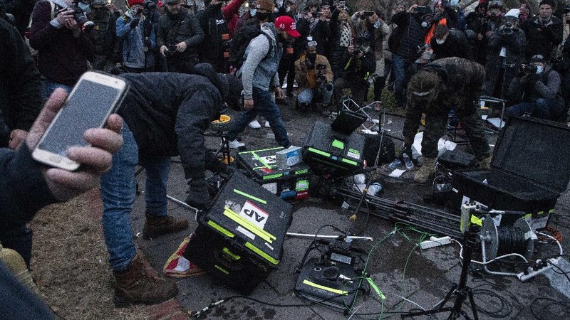 Demonstrators break TV equipment outside the the U.S. Capitol on Wednesday, Jan. 6, 2021, in Washington.  (AP Photo/Jose Luis Magana)