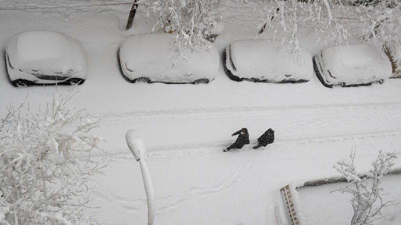 Two men walk slowly in the middle of a street after a heavy snowfall in Madrid, Spain, Saturday, Jan. 9, 2021. Spain is on high alert as a cold snap is covering much of the country with snow disrupting road, sea, rail and air traffic with the capital, Madrid enduring what the city's mayor described as 