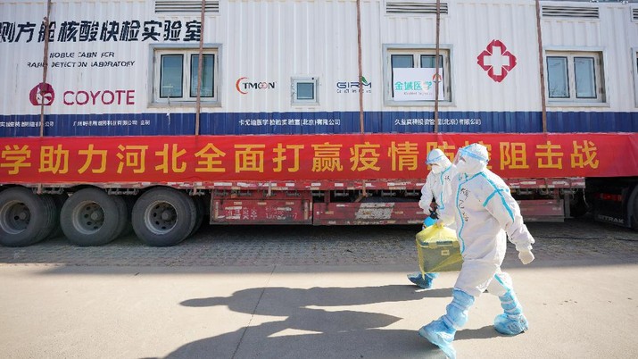 Virus Outbreak China In this photo released by China's Xinhua News Agency, workers carry a container of coronavirus test samples outside of a residential neighborhood in Shijiazhuang in northern China's Hebei Province, Friday, Jan. 8, 2021. A city in northern China is offering rewards of 500 yuan ($77) for anyone who reports on a resident who has not taken a recent coronavirus test. The offer from the government of Nangong comes as millions in the city and its surrounding province of Hebei are being tested as part of efforts to control China's most serious recent outbreak of COVID-19.(Mu Yu/Xinhua via AP)
