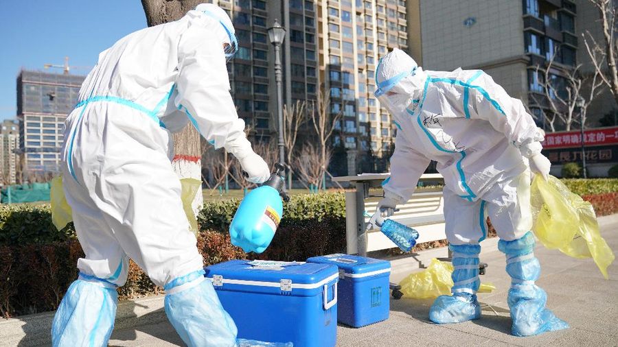 In this photo released by China's Xinhua News Agency, workers disinfect containers of coronavirus test samples outside of a residential neighborhood in Shijiazhuang in northern China's Hebei Province, Friday, Jan. 8, 2021. A city in northern China is offering rewards of 500 yuan ($77) for anyone who reports on a resident who has not taken a recent coronavirus test. The offer from the government of Nangong comes as millions in the city and its surrounding province of Hebei are being tested as part of efforts to control China's most serious recent outbreak of COVID-19.(Mu Yu/Xinhua via AP)