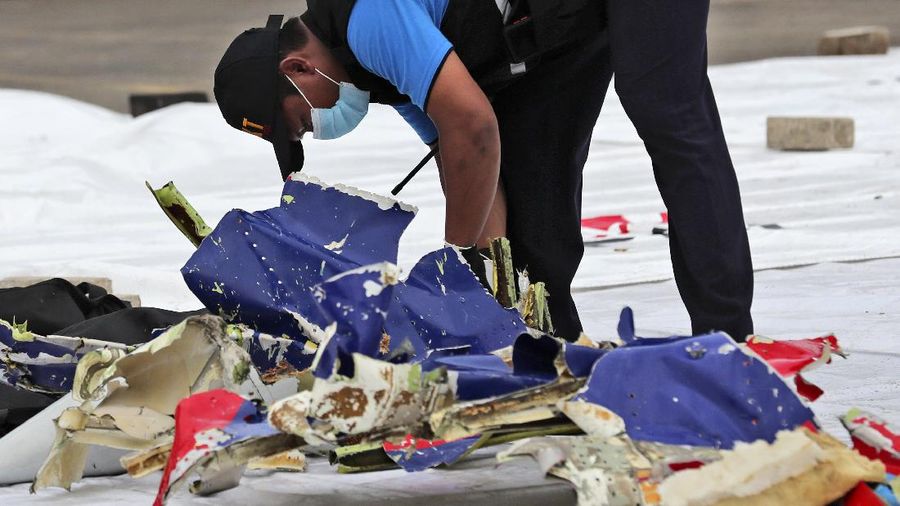 An investigator of Indonesian National Transportation Safety Committee inspects parts of Sriwijaya Air Flight 182 that crashed in the waters off Java Island, at Tanjung Priok Port in Jakarta, Indonesia, Sunday, Jan. 10, 2021. Indonesian rescuers pulled out body parts, pieces of clothing and scraps of metal from the Java Sea early Sunday morning, a day after the Boeing 737-500 with dozens of people onboard crashed shortly after takeoff from Jakarta, officials said. (AP Photo/Tatan Syuflana)