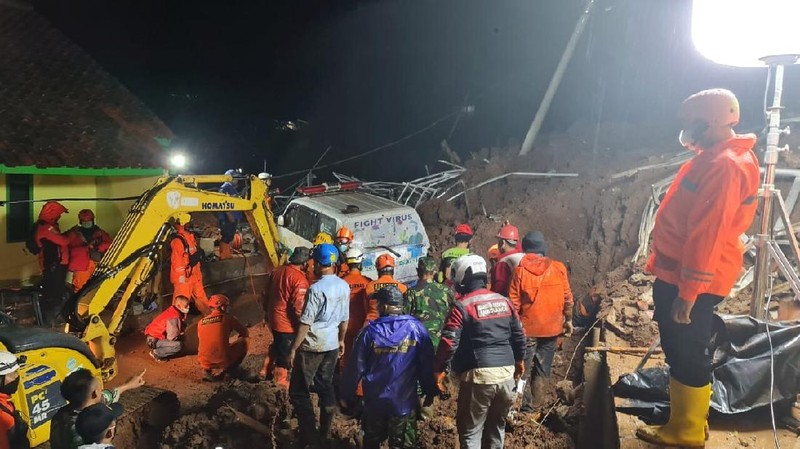 In this photo provided by the Indonesian National Disaster Mitigation Agency, rescuers work the scene of a landslide in Cihanjuang village, Indonesia, early Sunday, Jan. 10, 2021. Two landslides in the Sumedang district of West Java province triggered by heavy rain in Indonesia left multiple people dead and injured, officials said Sunday.  (Indonesian National Disaster Mitigation Agency via AP)