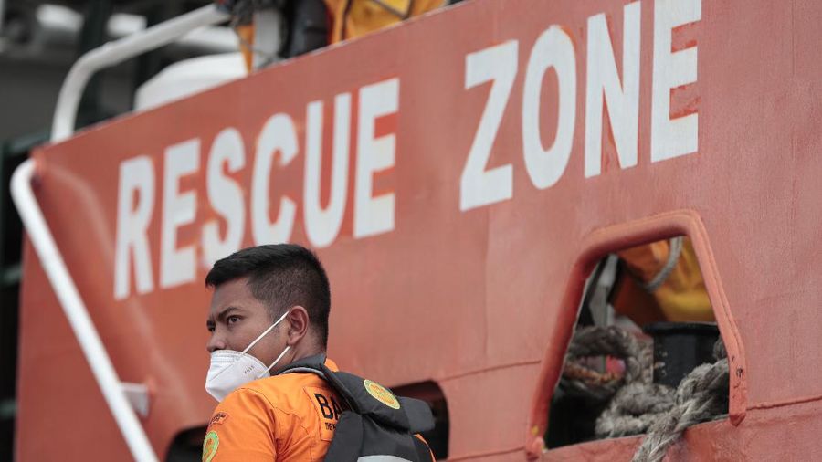 A Member of Nationl Search and Rescue Agency (BASARNAS) stands on a rescue ship prepared for a search for Sriwijaya Air's passenger jet that crashed off Java island, at Tanjung Priok Port in Jakarta, Indonesia, Sunday, Jan. 10, 2021. Indonesian rescuers pulled out body parts, pieces of clothing and scraps of metal from the Java Sea early Sunday morning, a day after a Boeing 737-500 with dozens of people onboard crashed shortly after takeoff from Jakarta, officials said. (AP Photo/Dita Alangkara)