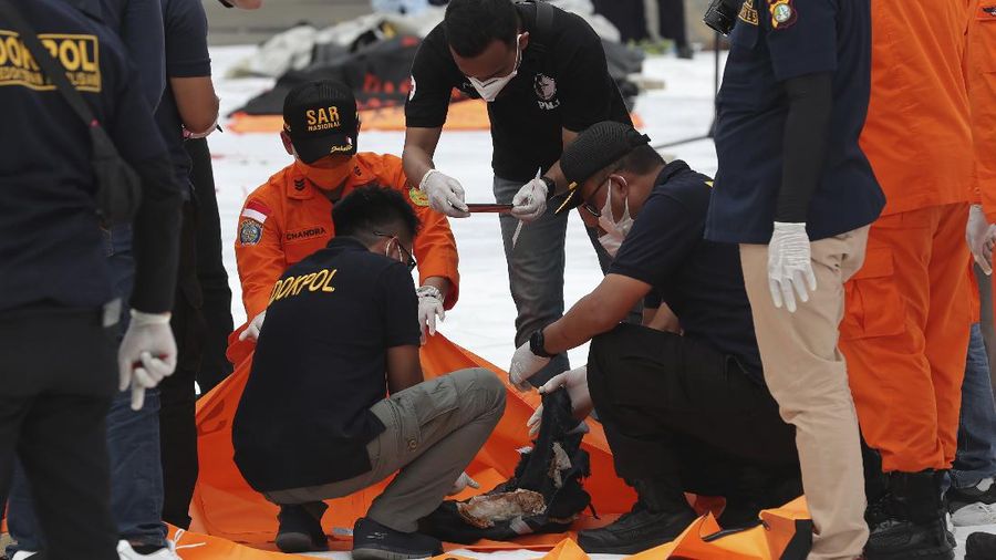 Tim penyelamat membawa kantong jenazah berisi jasad manusia yang ditemukan dari perairan tempat jet penumpang Sriwijaya Air jatuh, di Pelabuhan Tanjung Priok di Jakarta, Indonesia, Minggu, 10 Januari 2021. (AP Photo/Tatan Syuflana)