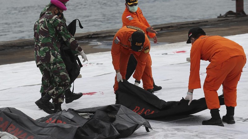 Tim penyelamat membawa kantong jenazah berisi jasad manusia yang ditemukan dari perairan tempat jet penumpang Sriwijaya Air jatuh, di Pelabuhan Tanjung Priok di Jakarta, Indonesia, Minggu, 10 Januari 2021.(AP Photo/Tatan Syuflana)