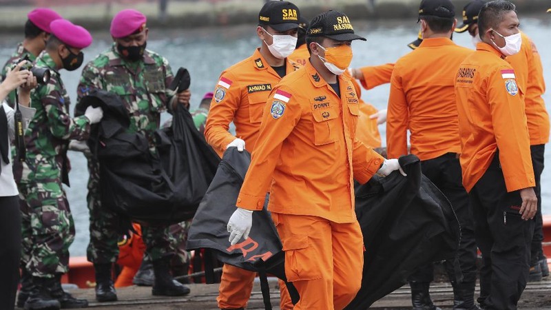 Tim penyelamat membawa kantong jenazah berisi jasad manusia yang ditemukan dari perairan tempat jet penumpang Sriwijaya Air jatuh, di Pelabuhan Tanjung Priok di Jakarta, Indonesia, Minggu, 10 Januari 2021.(AP Photo/Tatan Syuflana)