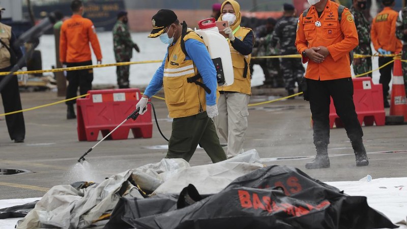 Tim penyelamat membawa kantong jenazah berisi jasad manusia yang ditemukan dari perairan tempat jet penumpang Sriwijaya Air jatuh, di Pelabuhan Tanjung Priok di Jakarta, Indonesia, Minggu, 10 Januari 2021.(AP Photo/Tatan Syuflana)