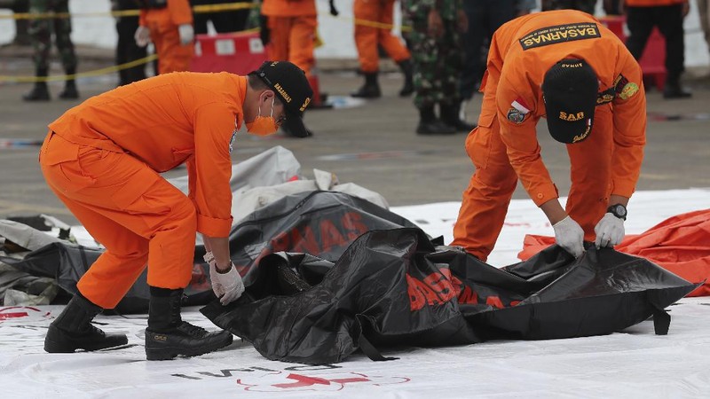 Tim penyelamat membawa kantong jenazah berisi jasad manusia yang ditemukan dari perairan tempat jet penumpang Sriwijaya Air jatuh, di Pelabuhan Tanjung Priok di Jakarta, Indonesia, Minggu, 10 Januari 2021.(AP Photo/Tatan Syuflana)