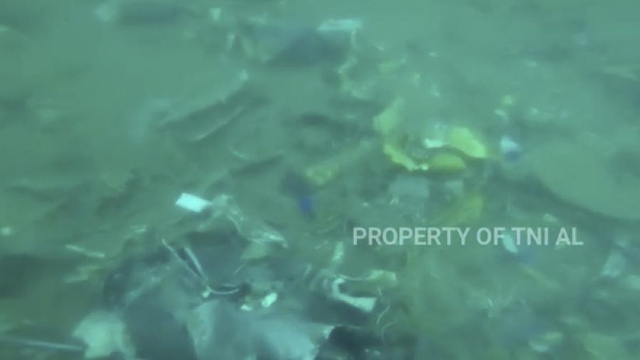 In this image made from undated video released by Indonesian Navy (TNI AL), divers points at debris strewn on the sea floor in Java Sea where Sriwijaya Air passenger jet crashed, in Indonesia. The search for the black boxes of a crashed Sriwijaya Air jet intensified Monday, Jan. 11, 2021, to boost the investigation into what caused the plane carrying dozens of people to nosedive at high velocity into the Java Sea. (Indonesian Navy via AP)