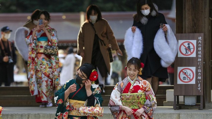 Sejumlah warga menggunakan Kimono di Tokyo, Jepang. Kimono-clad women wearing face masks to protect against the spread of the coronavirus pose for a selfie while visiting a Shinto Shrine as they celebrate Coming-of-Age, turning 20 years old, the traditional age of adulthood in Japan, Monday, Jan. 11, 2021, in Tokyo. Most of the city hosted ceremonies were cancelled due to a state of emergency. (AP Photo/Kiichiro Sato)
