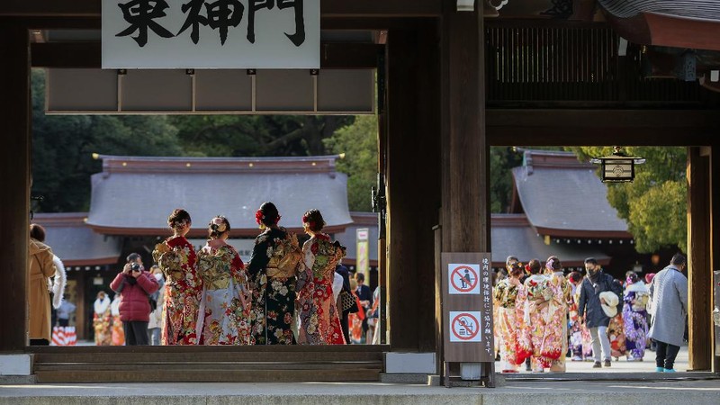 Kimono-clad women wearing face masks to protect against the spread of the coronavirus sit with social distancing for a Coming-of-Age ceremony in Yokohama, near Tokyo, Monday, Jan. 11, 2021. The Tokyo area has been under a state of emergency since Friday to try to stop the spread of the virus. (AP Photo/Koji Sasahara)