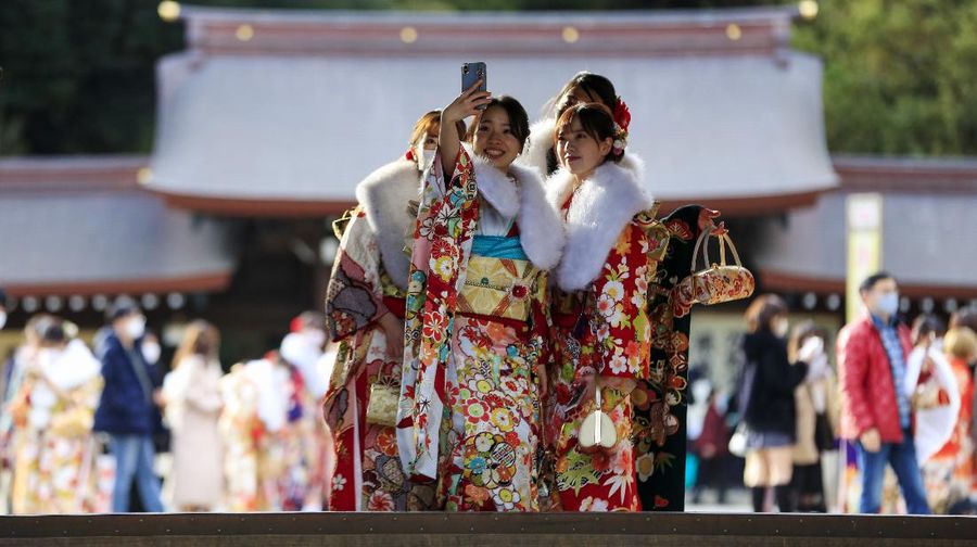 Kimono-clad women wearing face masks to protect against the spread of the coronavirus pose for a selfie while visiting a Shinto Shrine as they celebrate Coming-of-Age, turning 20 years old, the traditional age of adulthood in Japan, Monday, Jan. 11, 2021, in Tokyo. Most of the city hosted ceremonies were cancelled due to a state of emergency. (AP Photo/Kiichiro Sato)