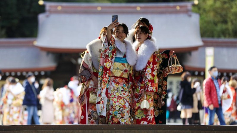 Kimono-clad women wearing face masks to protect against the spread of the coronavirus sit with social distancing for a Coming-of-Age ceremony in Yokohama, near Tokyo, Monday, Jan. 11, 2021. The Tokyo area has been under a state of emergency since Friday to try to stop the spread of the virus. (AP Photo/Koji Sasahara)