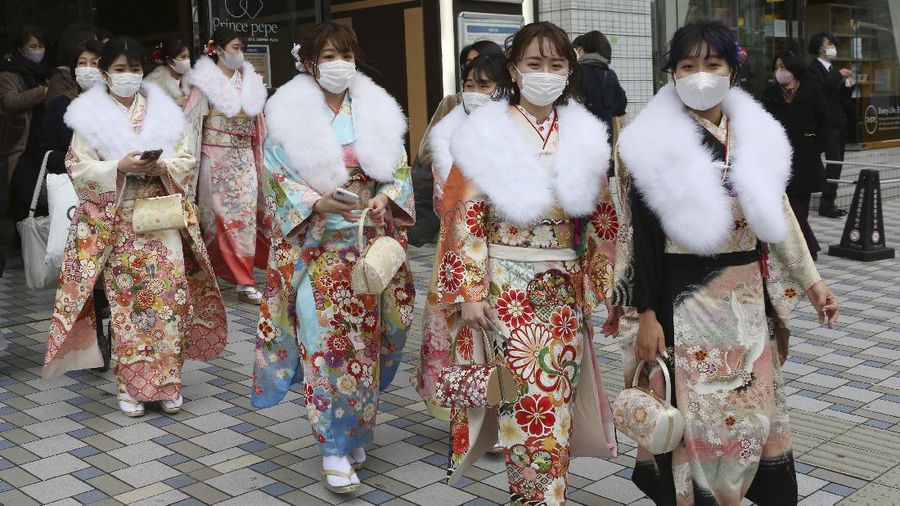 Kimono-clad women wearing face masks to protect against the spread of the coronavirus walk out after a Coming-of-Age ceremony in Yokohama, near Tokyo, Monday, Jan. 11, 2021. The Tokyo area has been under a state of emergency since Friday to try to stop the spread of the virus. (AP Photo/Koji Sasahara)