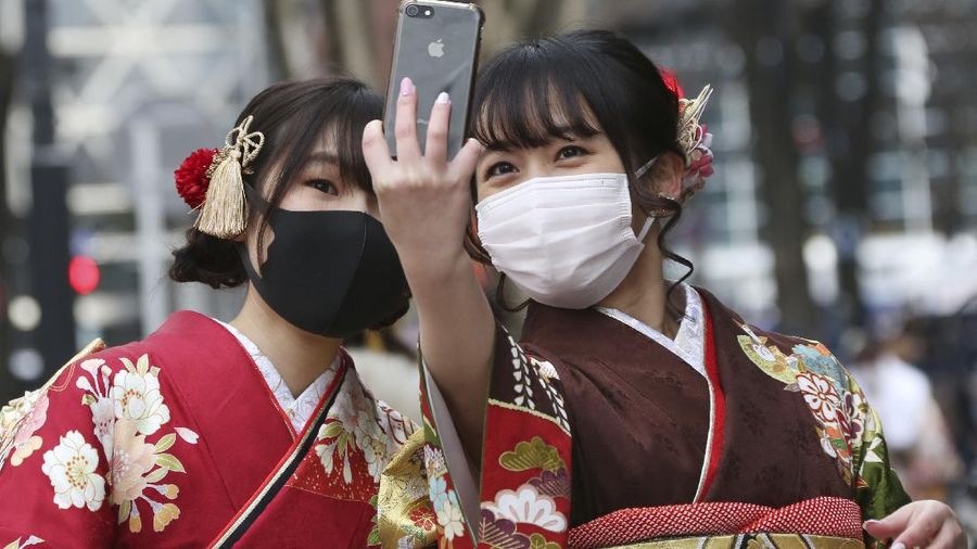 Kimono-clad women wearing face masks to protect against the spread of the coronavirus pose for a selfie together following a Coming-of-Age ceremony in Yokohama, near Tokyo, Monday, Jan. 11, 2021. (AP Photo/Koji Sasahara)