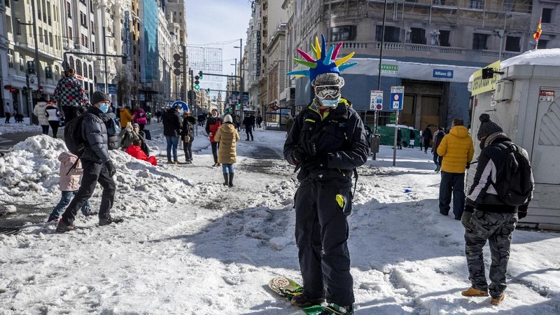 A man snowboards at the Gran Via avenue in downtown Madrid, Spain, Sunday, Jan. 10, 2021. A large part of central Spain including the capital of Madrid are slowly clearing snow after the country's worst snowstorm in recent memory. (AP Photo/Manu Fernandez)