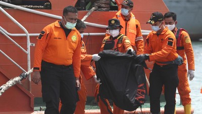 Rescuers carry debris found in the waters around the location where Sriwijaya Air passenger jet crashed at Tanjung Priok Port in Jakarta, Indonesia, Monday, Jan. 11, 2021. The search for the black boxes of a crashed Sriwijaya Air jet has intensified to boost the investigation into what caused the plane carrying dozens of people to nosedive into Indonesia seas. The Boeing 737-500 jet disappeared during heavy rain on Saturday. (AP Photo/Achmad Ibrahim)
