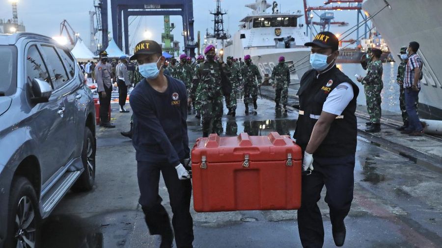 Members of the National Transportation Safety Committee carry a box containing the flight data recorder of Sriwijaya Air flight SJ-182 retrieved from the Java Sea where the passenger jet crashed at the Tanjung Priok Port, Tuesday, Jan. 12, 2021. Indonesian navy divers searching the ocean floor on Tuesday recovered the flight data recorder from a Sriwijaya Air jet that crashed into the Java Sea with 62 people on board, Monday, Jan. 11, 2021. (AP Photo/Dita Alangkara)