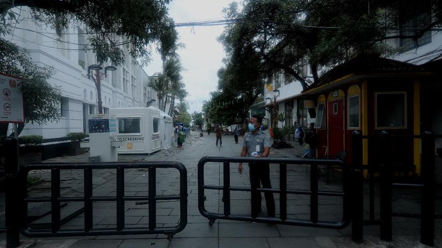 Sejumlah warga melewati Jalan Pintu Besar Utara yabg ditutup di kawasan Kota Tua, Jakarta, Rabu (13/1/2021). Pemerintah Kota Administrasi Jakarta Barat menutup sejumlah ruas jalan menuju kawasan wisata Kota Tua selama Pemberlakuan Pembatasan Kegiatan Masyarakat (PPKM) di DKI Jakarta pada 11 Januari hingga 25 Januari 2021 untuk mencegah kerumunan. (CNBC Indonesia/Tri Susilo)
Pantauan CNBC Indonesia kemacetan tidak terhindarkan kendaraan dari arah Harmoni menuju Jalan Pintu Besar Utara karena banyak pengguna jalan yang belum mengetahui penutupan jalur. 
Salah satu satgas Kota Tua yang tidak ingin disebutkan namanya mengatakan 